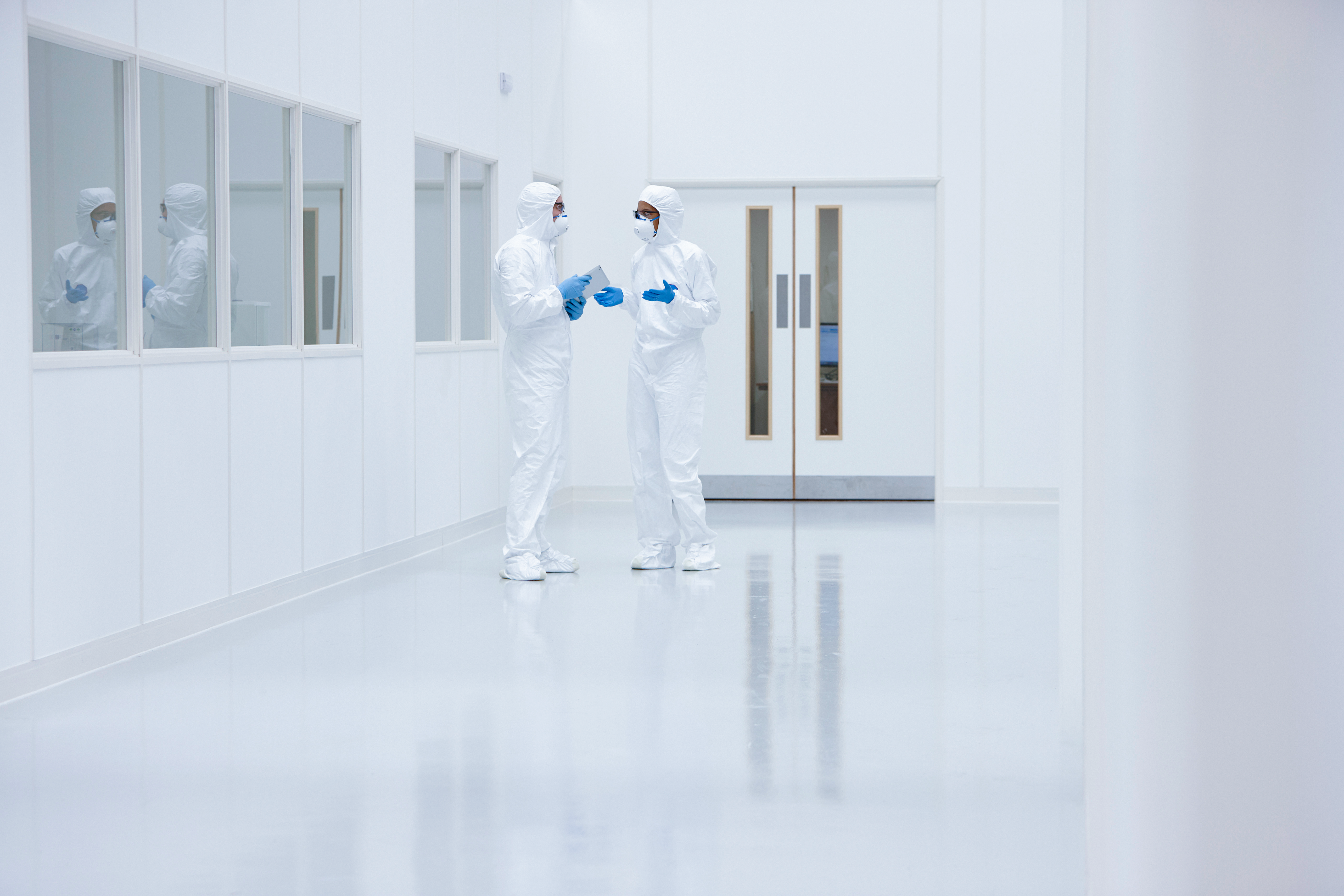 Two people in safety equipment stand and talk in a lab environment